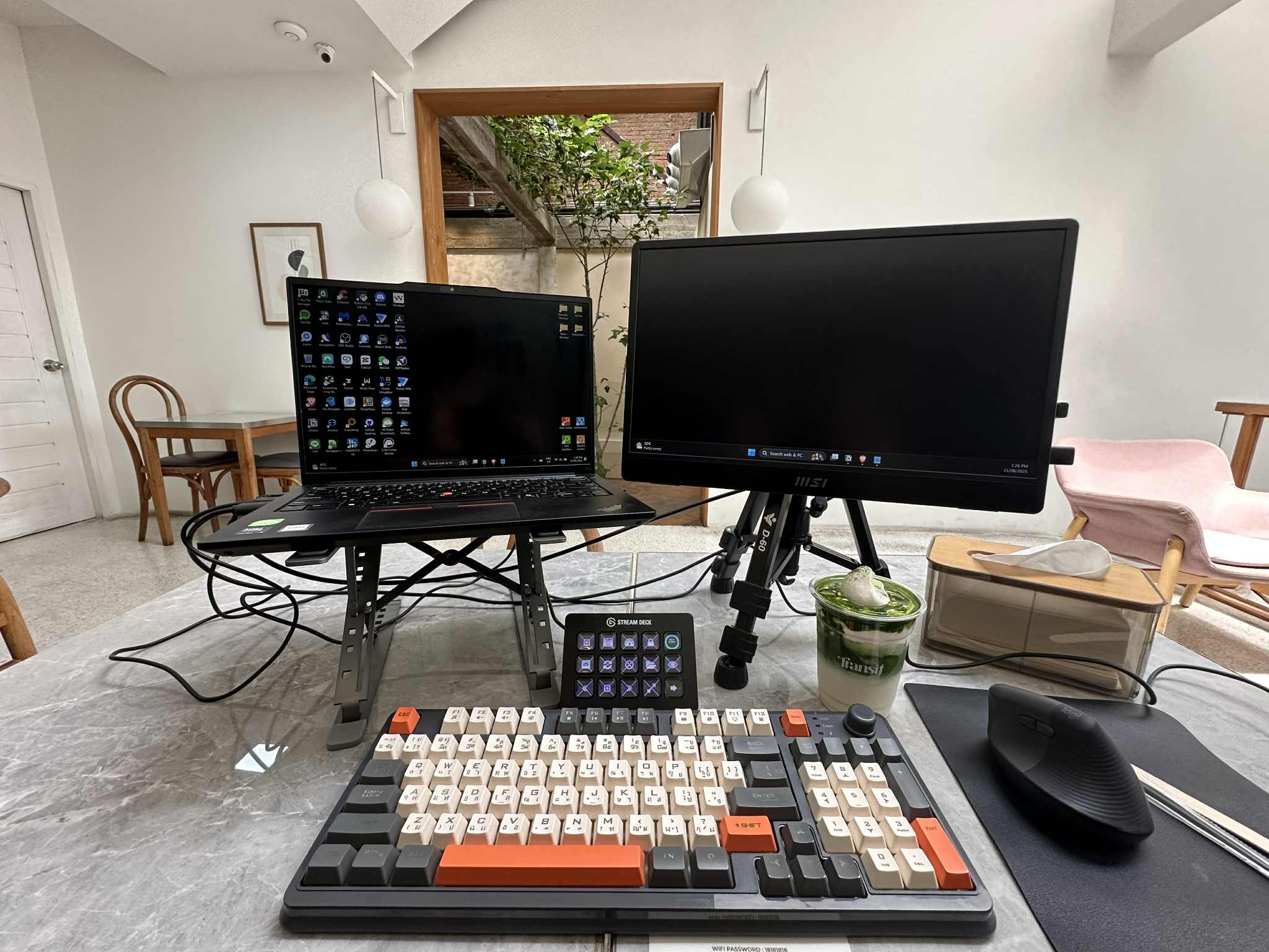 Remote work setup in Chiang Mai with dual monitors, laptop, and mechanical keyboard.