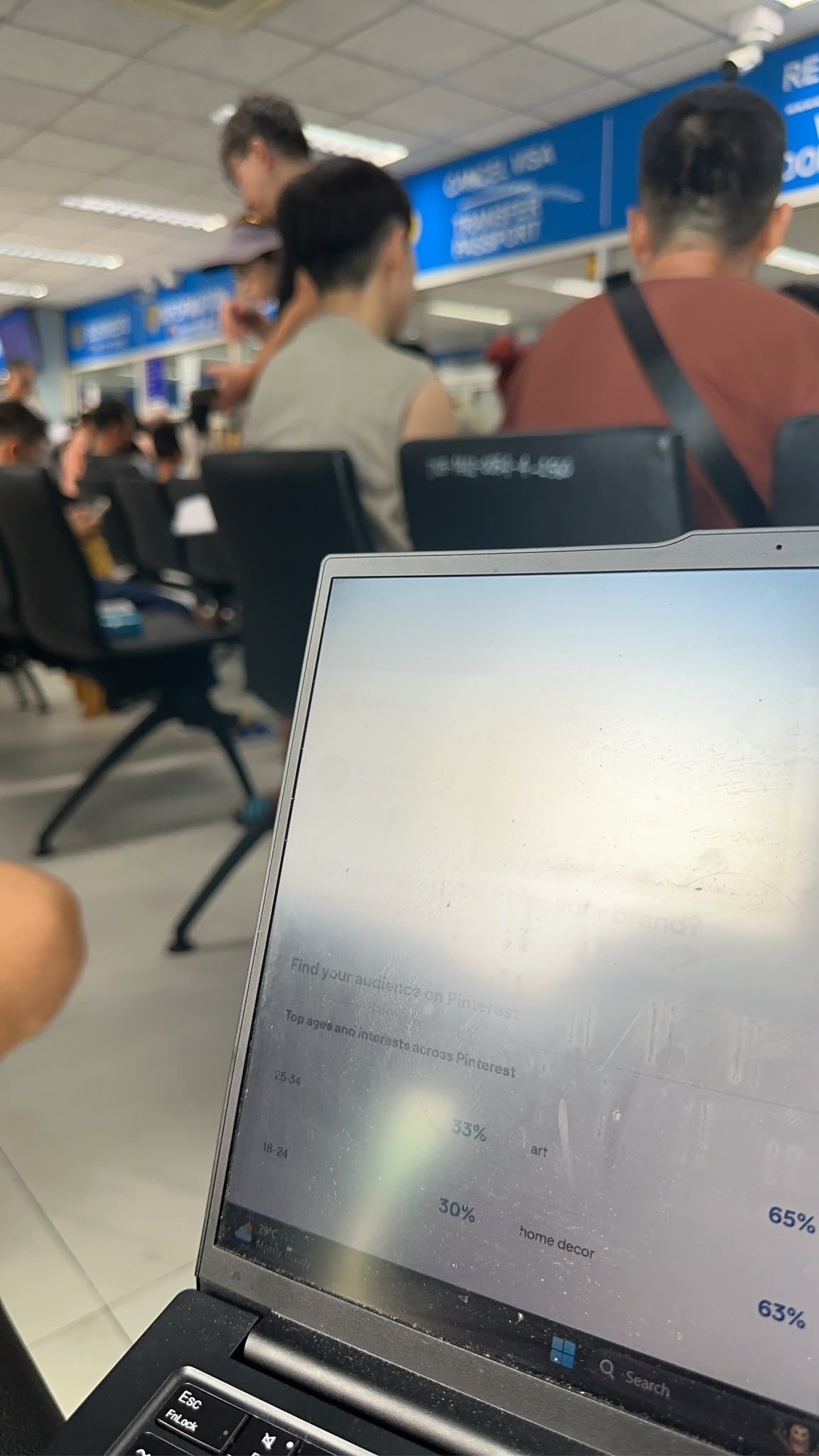 Working from a laptop in the immigration hall queue, CANCEL VISA sign overhead