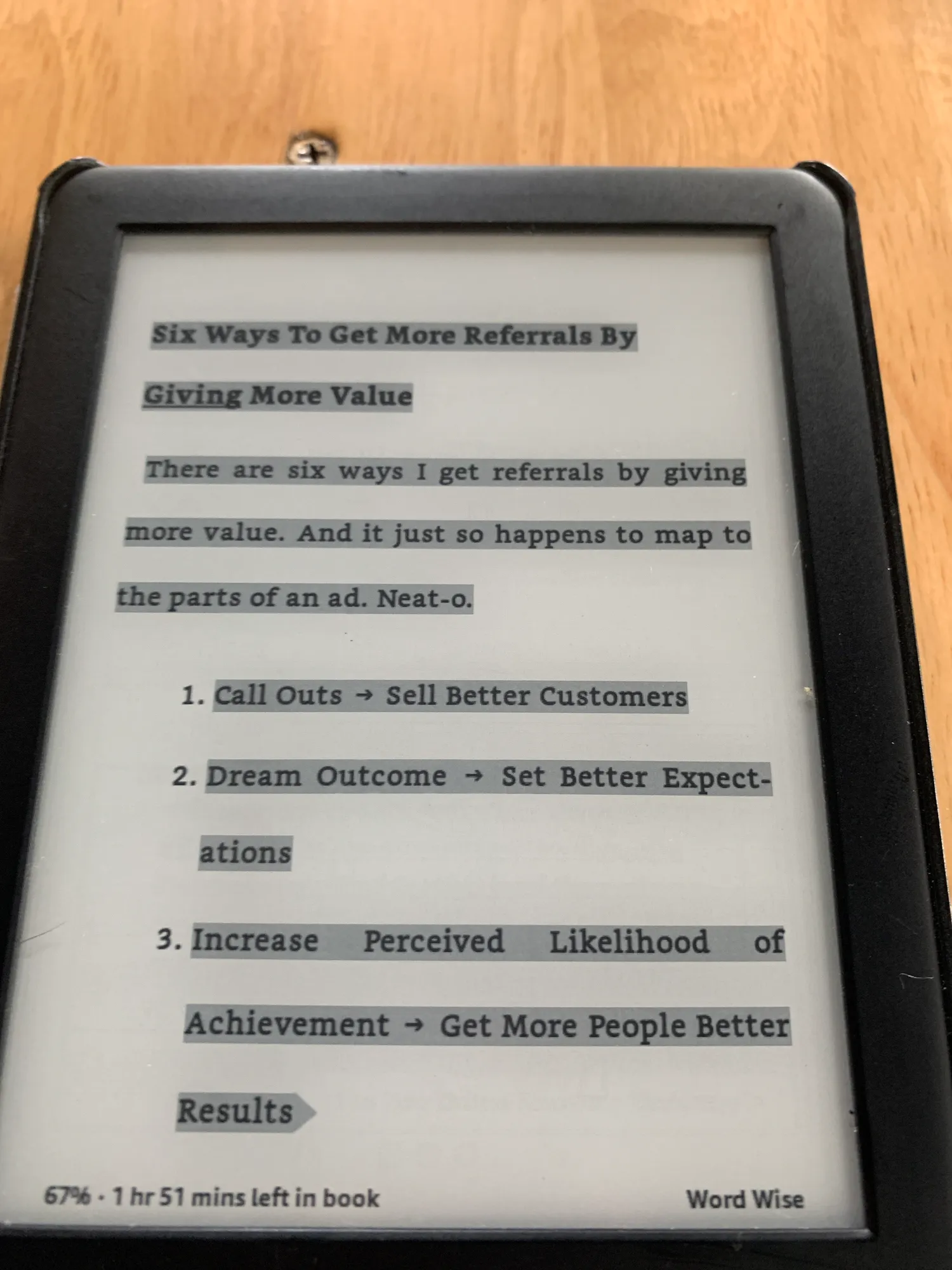 A Kindle showing a highlighted passage about getting referrals by giving more value