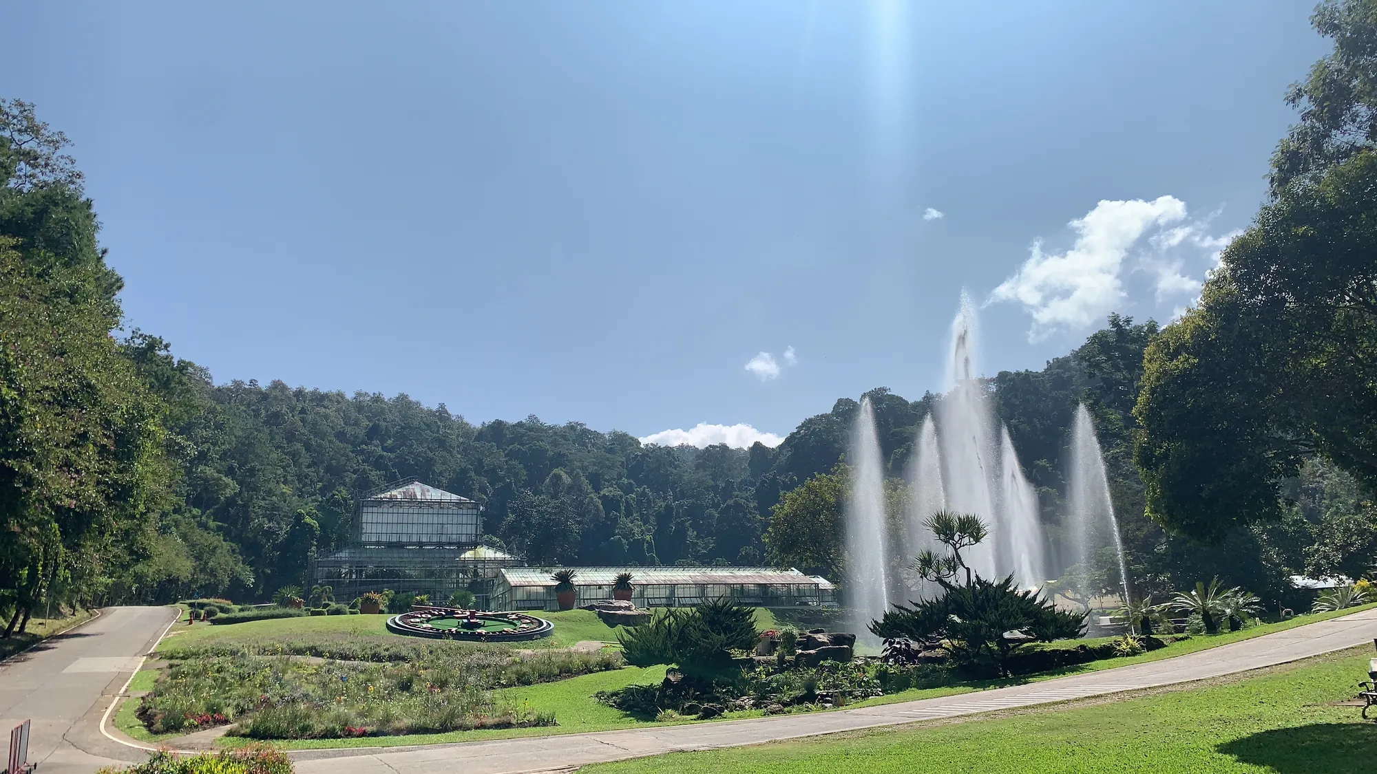 The glasshouse complex at Queen Sirikit Botanic Garden, with a floral clock and fountain on the lawn below